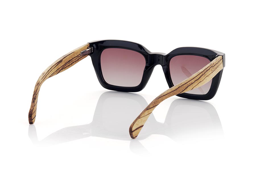 Wood eyewear of Walnut OONA. OONA sunglasses are the perfect accessory to complete your look. With a satin black front frame with a square shape and rounded corners, these glasses have a modern and sophisticated touch. The wide temples are made of zebrano wood, creating a beautiful color contrast. These glasses are ideal for women looking for something different and unique. In addition, they mount brown gradient lenses that offer protection against UV rays. Feel elegant and protected from the sun with OONA sunglasses. for Wholesale & Retail | Root Sunglasses® 